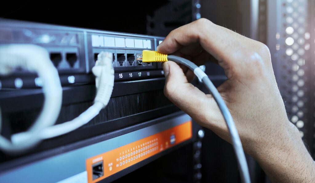 Hands, network engineer and server cable in server room for data, internet or web connection. Cyber